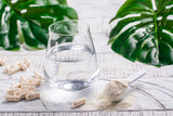 Glass of water, collagen powder and pills on white wooden table