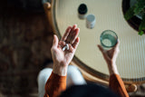 Woman with two supplement pills in her left palm and a glass of water in her right hand