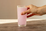woman's hand holding a glass of pink electrolytes dissolved in water