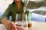 woman pouring water from a pitcher into a glass