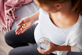 pregnant woman with a glass of water and supplement tablets and pills in her other hand