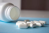 magnesium tablets and its bottle on a blue surface