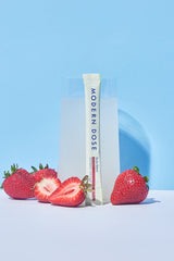 Modern Dose Biotic Blend drink with stick pack leaning against the glass and strawberries surrounding the glass on a blue background - www.moderndose.com
