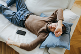 tired man laying on his couch with eyes closed