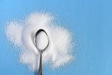 stevia powder, a spoon, and a blue background