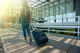 woman with a backpack and suitcase walking outside of the airport