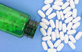 A group of white magnesium vitamin pills with a green jar on a blue background.