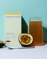 Modern Dose cognition boost drink with its supplement box and passion fruit on a light blue background - www.moderndose.com