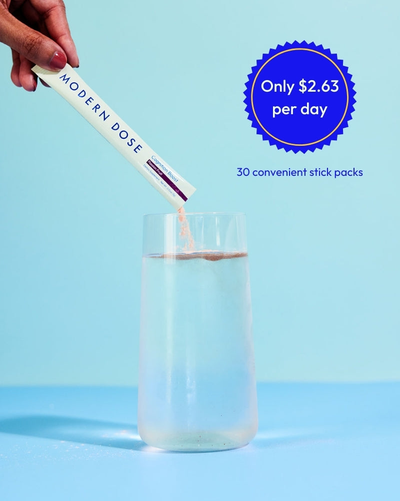 Modern Dose Cognition Boost stick pack being added to a glass of water with pricing and quantity information on a blue background - www.moderndose.com