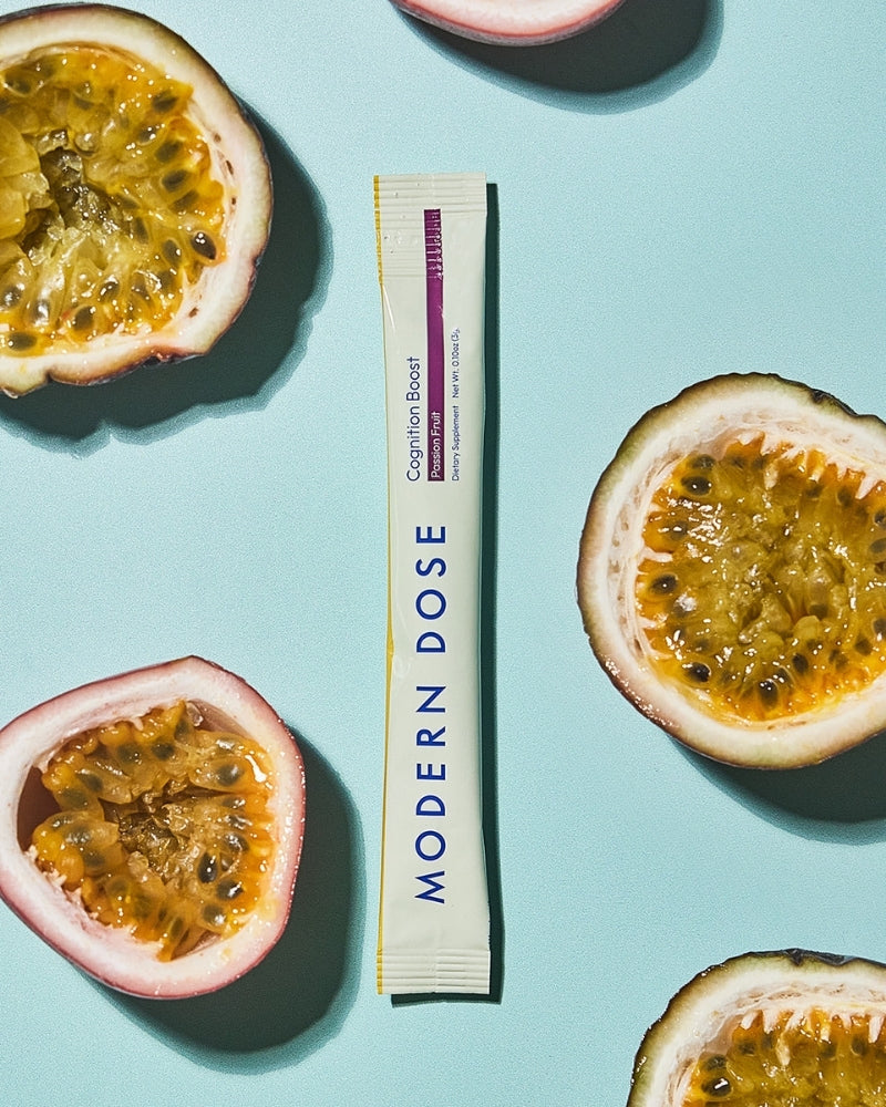 Modern Dose Cognition Boost supplement stick with halved passion fruits on a light blue background - www.moderndose.com