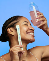 Happy woman holding a Modern Dose Essential Health stick pack and a glass of Modern Dose Essential Health drink - www.moderndose.com