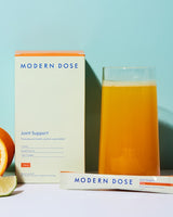 Modern Dose Joint Support drink in a glass next to its supplement box and stick pack on a light blue background - www.moderndose.com