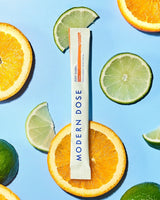 Modern Dose supplement stick pack surrounded by oranges and limes on a blue background - www.moderndose.com