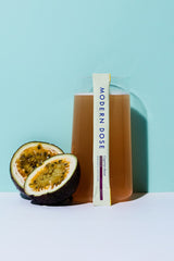 Modern Dose Cognition Boost drink with stick pack leaning against it and passion fruit next to it on a blue background - www.moderndose.com