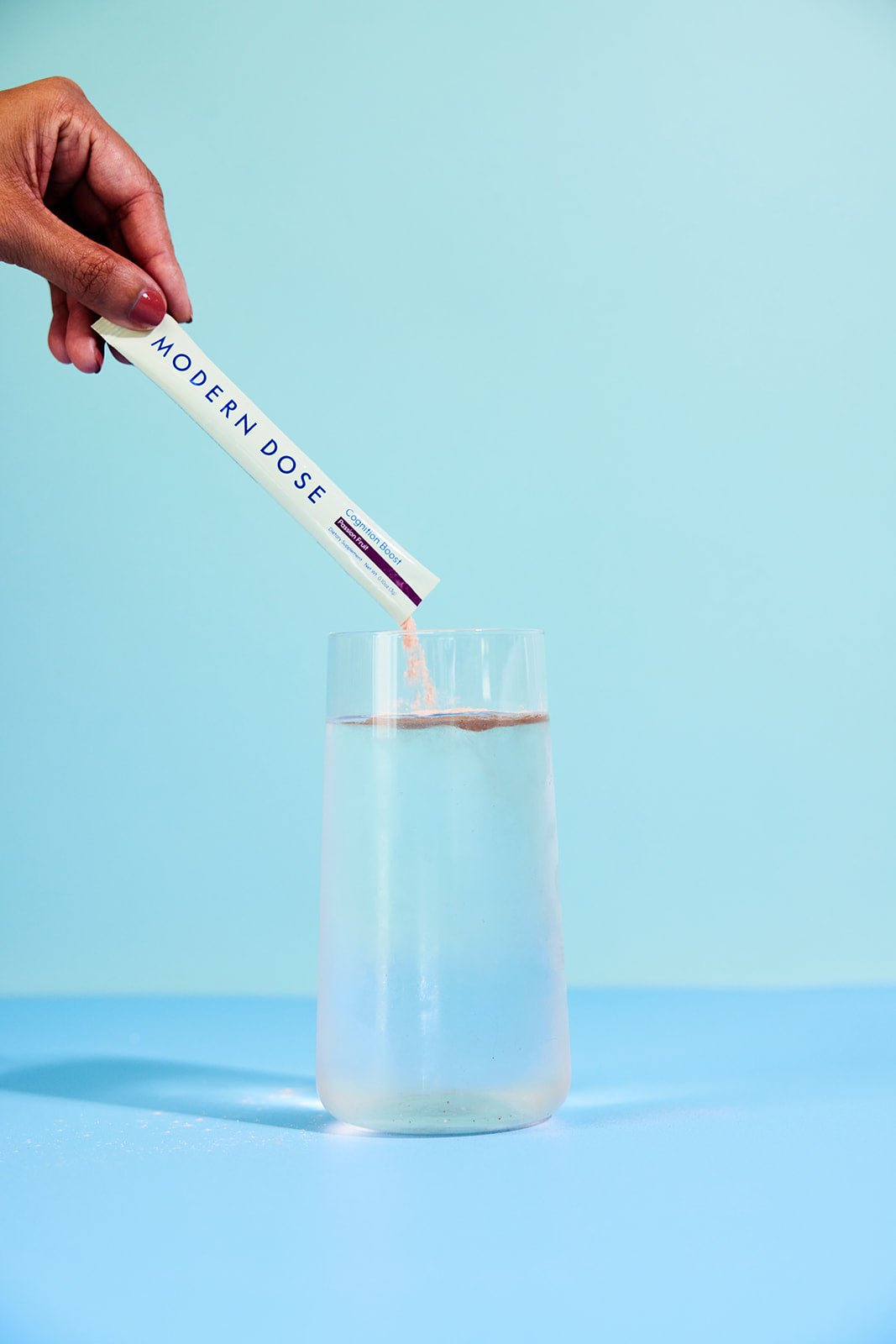Modern Dose Cognition Boost powder being poured into a glass of water - moderndose.com