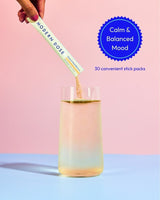 Modern Dose Stress & Mood Balance supplement stick pack product being added to a glass of water with a pink and blue background and text about calm & balanced mood