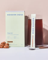 Modern Dose sleep aid supplement stick pack and box with a glass of Sleep Aid drink and salted caramel on a light background