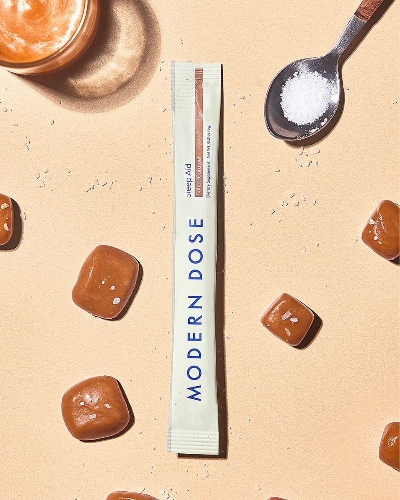Modern Dose supplement stick pack surrounded by caramels on a beige background